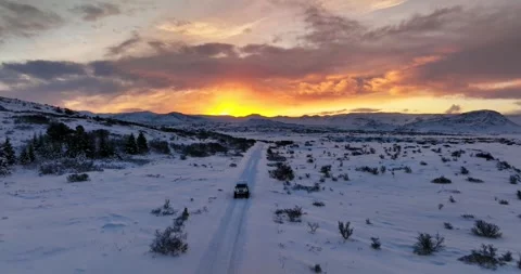 4x4 driving toward a vivid sunset on a snowy road in Heiðmörk, Iceland 库存影片 341478320