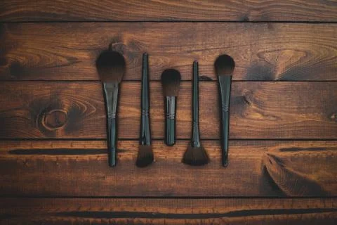 5 assorted makeup brushes on a brown rustic wood background Stock Photos