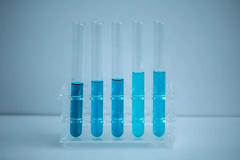 5 blue test tubes placed in a medical tube rack with a white background. Stock Photos