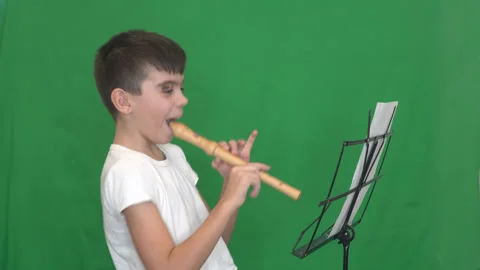 5 brunette boy with a white jacket plays the recorder, music stand, notes Stock Footage 266450747