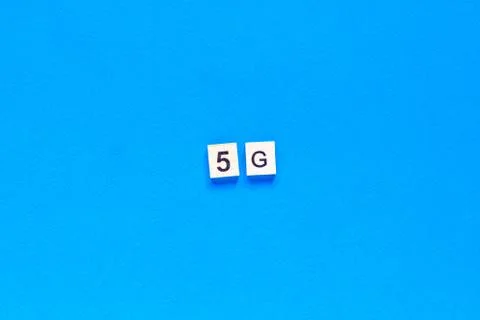 5 G. Five G's, written in wooden letters on a blue background. top view. Flat Stock Photos