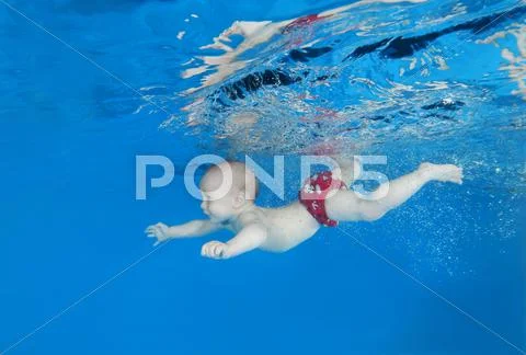 5 months infant boy learning to swim underwater in waterbaby class in the pool Stock Photos