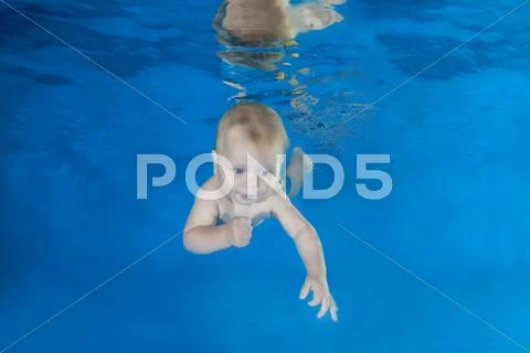 5 months infant boy learning to swim underwater in waterbaby class in the pool Stock Photos