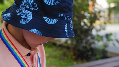 A 5-year-old boy in a blue bucket hat eats ice cream on the street Stock Footage 279064452