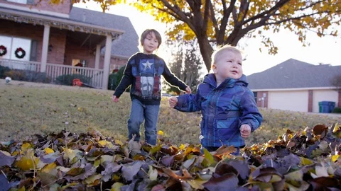 5 year old boy comforts grumpy toddler, who pushes him away with lens flare Stock-Footage 93886603