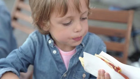 5 year old boy in denim shirt eating delicious hot dog. Vidéo 92791201
