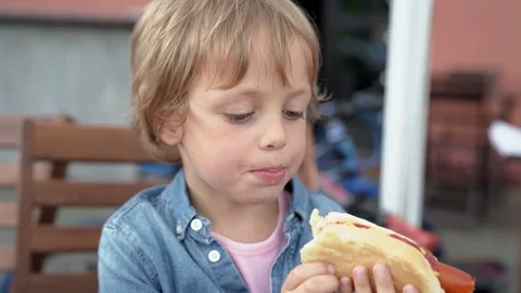 5 year old boy in denim shirt eating delicious hot dog. Stock Footage 92791909
