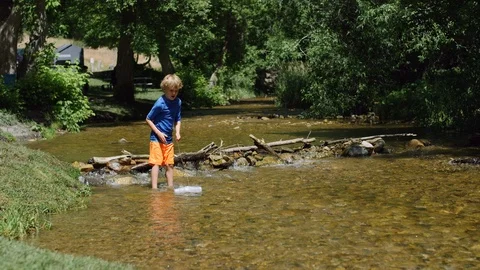 5 year old boy drops a homemade boat into a river and follows it downstream 8K Видео 122531329