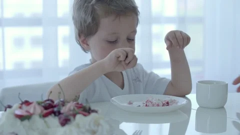5 year old boy eats dessert at the white table Stock Footage 92381351