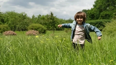 A 5-year-old boy is hiding in a field of tall grass, jumping out and laughing. Stock Footage 312515559