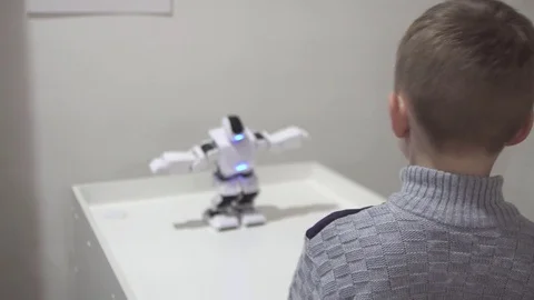 5 year old boy looks at the dancing modern robot Video stock 83431312