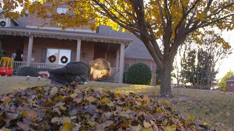 5 year old boy picks up and throws leaves at sunset 库存影片 93886924