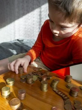 5-year-old boy puts euro cent coins in piles,wooden box scattered coins column Stock Photos