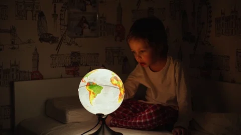5 year old boy sitting in bed at night rotating the globe and dreams of Stock Footage 101029560