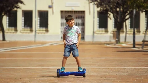 5-year-old boy skates safely and confident with a hoverboard in town square. Stockbeeldmateriaal 137522797