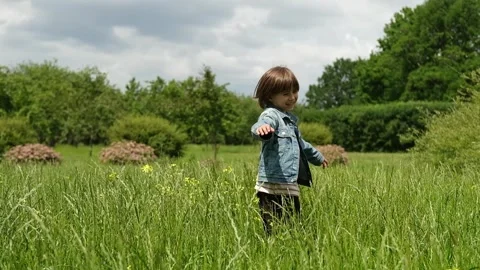 A 5-year-old boy is spinning around on his own axis in a field and enjoying a Stock Footage 312515606