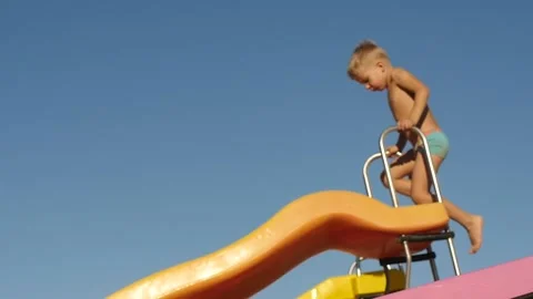 5 years old boy on the playground going up and sliding down from hill Stock Footage 167234346