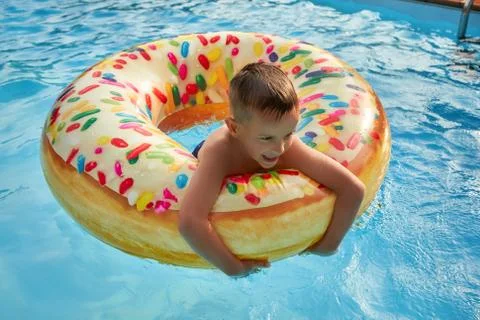 5 years old Boy in swimming pool on inflatable colorful ring Stock Photos