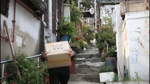 5089 Long Take of a Man Carrying a Heavy Load Through an Old Korean Alley Stock Footage 338224730