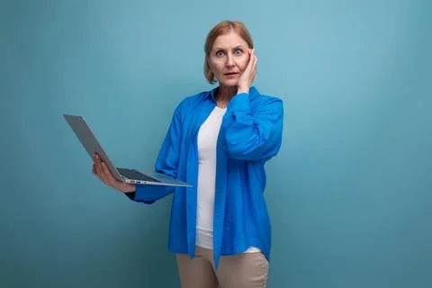 50s middle aged business woman working as freelancer with laptop on blue Stock Photos