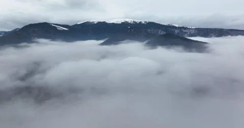 A 5.1k drone video flying through a layer of fog with a moutain view on the back Stock Footage 174366242