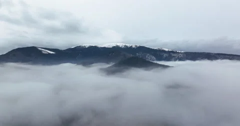 A 5.1k drone video flying through a layer of fog with a moutain view on the back Stock Footage 174373380