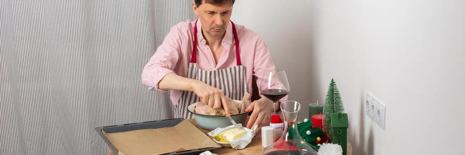 A 53-year-old man is preparing chicken for pre-Christmas dinner. He seasons t Stock Photos