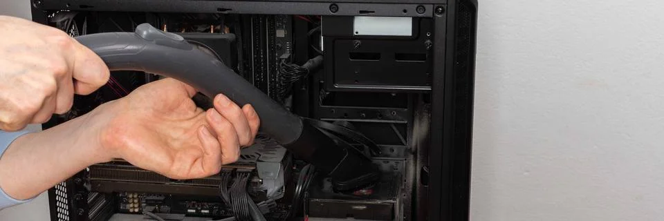 A 53-year-old man uses a vacuum attachment to remove dust from a computer sys Stock Photos