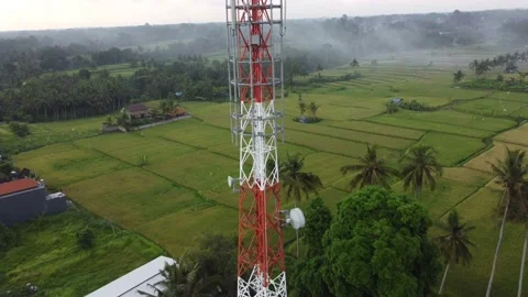5g telecom tower close up drone aerial revealing green rice field plowed land Stock Footage 143635944
