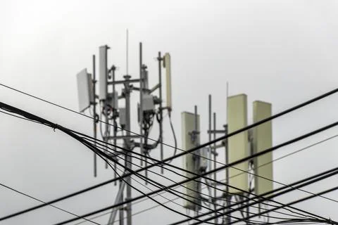 5G telecom tower mounted on rooftop building blue sky urban communication s.. Stock Photos