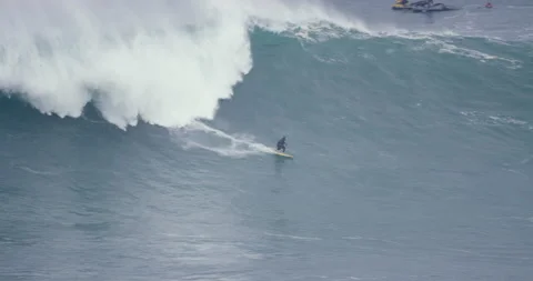 5K Distant view of pro surfer riding on big ocean wave during cloudy day Stock Footage 157714572
