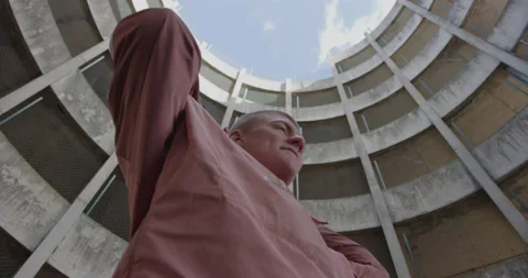 5K SLOW MOTION. LOW ANGLE SHOT OF YOUTH IN AN URBAN CAR PARK PUTTING UP HOOD Stock Footage 136561856