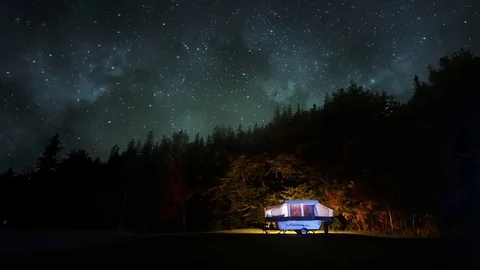 5th-wheel camper in the woods under a starry night sky Stock Footage 86777828
