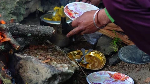 6-04-24; A man mixing pulao in a cooker near a wood fire in Himachal Pradesh. Stock Footage 272573370