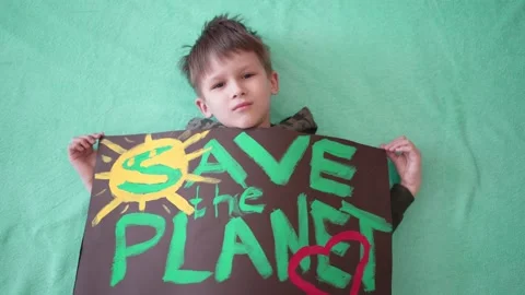 A 6-7 year old child is holding a poster with the words "Save the Planet" Stock Footage 150852154