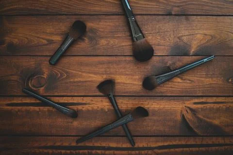 6 assorted makeup brushes on a brown rustic wood background. Stock Photos