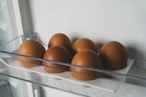 6 brown chicken eggs in an empty colloquially fridge. half dozen eggs in the  Stock Photos