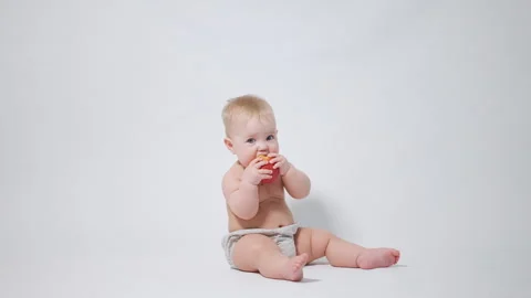 A 6-month-old baby eats a red apple, video shot against a light background Stock-Footage 242780024