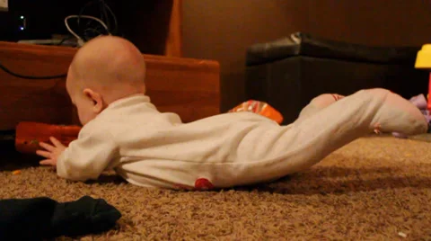 6 month old balances on her tummy while playing with a wrapper Stock Footage 35799623
