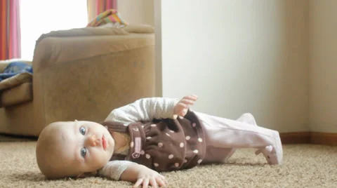 6 month old blinks at the camera before flipping up onto her belly Video stock 35798427