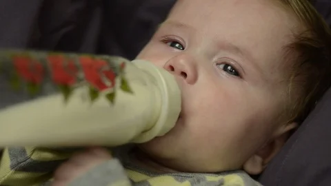 A 6 month old boy drinks milk from a bottle and looks at the camera. Stock Footage 114968090