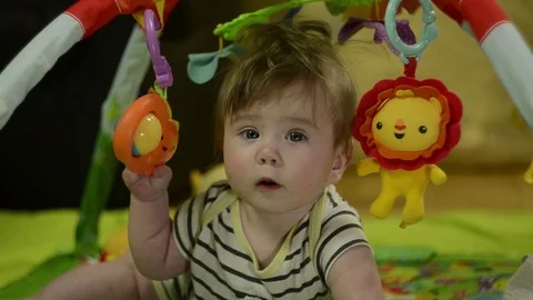 A 6 month old boy with long blond hair, plays with a mobile Stock Footage 114967933