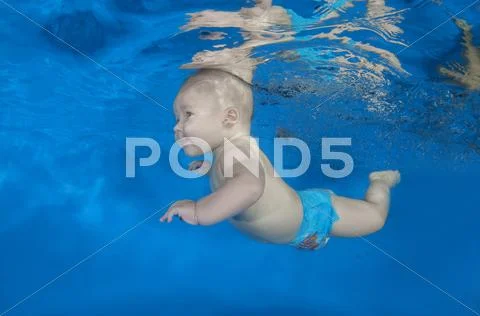 6 months infant boy learning to swim underwater in waterbaby class in the pool Stock Photos