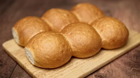 6 pieces of fresh bread rolls on a wooden cutting board. Stock Footage 135306629