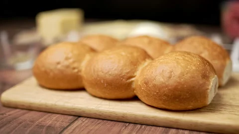 6 pieces of fresh bread rolls on a wooden cutting board. Stock Footage 135308254