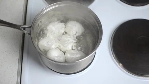 6 six white eggs are boiled in a metal pan in water on an electric stove Stock Footage 123832739