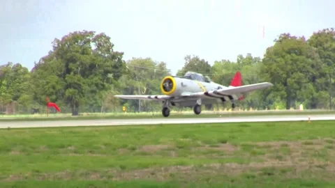 An AT-6 Texan pilot trainer aircraft lands at close range, with a waiting B-29 库存影片 147163785