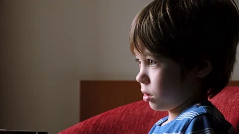 6 year boy looking at screen. Child is watching TV, cartoons or video. Home Stock Footage 235896584
