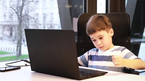 6 year boy using laptop looking at screen in a computer class. Teacher comes and Stock Footage 265059796