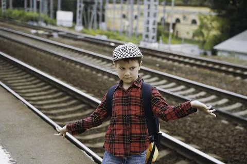 6 year old boy with backpack. posing on the train platform on summer day. rai Foto stock